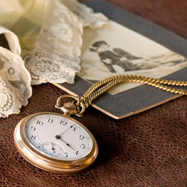 Antique lady's lace handkerchief and man's pocket watch (belonged to my parents)on distressed leather background.  Selective focus on watch. Slight warm filter for antique effect. People in photo blurred & unrecognizable.SEE SERIES: